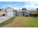 Charming single-story home featuring a well-maintained lawn, attached garage, and cozy front porch seating area at 4326 Great Lakes N Dr, Clearwater, FL 33762