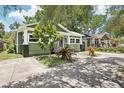 Green home showcasing its driveway, lovely yard plants, and a view of the neighbor's house at 6006 N Highland Ave, Tampa, FL 33604