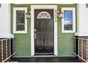 Close up of the black front door with a semicircle window, house number, and decorative lamps at 6006 N Highland Ave, Tampa, FL 33604