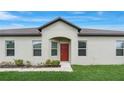 Inviting single-story home with a classic red front door and well-manicured landscaping at 13423 Crest Lake Dr, Hudson, FL 34669