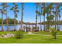 Picturesque backyard featuring a charming gazebo, fire pit, and lush landscaping along the waterfront at 17124 Crawley Rd, Odessa, FL 33556