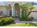 Arched entrance with pillars and glass front doors surrounded by colorful landscaping and a brick walkway at 17318 Emerald Chase Dr, Tampa, FL 33647