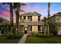 Two-story home with front porch and lush landscaping under a colorful sky at dusk surrounded by tall palm trees at 20039 Heritage Point Dr, Tampa, FL 33647