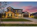 Charming two-story home featuring a manicured lawn, stone accents, and a spacious three-car garage at 32122 Wenlock Loop, Wesley Chapel, FL 33543