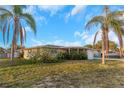 A charming single-story house with a quaint front yard, complemented by swaying palm trees at 3243 Eisenhower Dr, Holiday, FL 34691