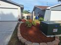 Well-kept side yard featuring a mulch bed with mature plants, utility access, and fence-lined property at 3357 Hunt Club Dr, Clearwater, FL 33761