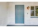 Close-up of a stylish blue front door framed by white brick, complemented by an outdoor light at 416 Flamingo Dr, Apollo Beach, FL 33572