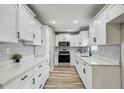 Bright kitchen with white cabinets, herringbone backsplash, stainless steel appliances, and wood-look flooring at 416 Flamingo Dr, Apollo Beach, FL 33572