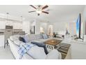 Bright living room with white walls, tile floors, modern ceiling fan and a large couch at 6398 Bar S Bar Trl, Zephyrhills, FL 33541