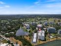 Aerial view of condo with community pool, manicured lawns, covered parking, and water view in Sarasota, Florida at 100 Oakmont Ln # 305, Belleair, FL 33756