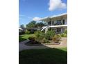 Exterior view of a white two story condo with landscaped garden and green lawn at 138 36Th N Ave # 206W, St Petersburg, FL 33704