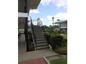 Exterior staircase with black railing leading to upper-level condos, surrounded by lush landscaping and mature trees at 138 36Th N Ave # 206W, St Petersburg, FL 33704