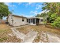 Backyard view showcasing the screened patio, partial fencing, and tropical foliage at 1472 Belcher S Rd, Largo, FL 33771