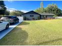 Well-kept home with a large front yard, a driveway with parked cars, and mature trees at 17933 Eagle Ln, Lutz, FL 33558