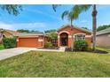 Inviting single-Gathering home featuring mature landscaping, a two-car garage, and covered front entry at 19156 Dove Creek Dr, Tampa, FL 33647