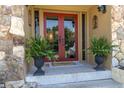 Inviting entryway featuring a vibrant red double door, stone accents, and lush ferns in decorative pots at 2287 Demaret Dr, Dunedin, FL 34698
