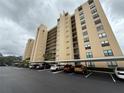View of condo building featuring parking and desert-style landscaping on an overcast day at 2621 Cove Cay Dr # 206, Clearwater, FL 33760