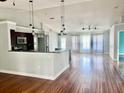 Bright, open-concept living room with hardwood flooring and modern lighting fixtures at 2841 S Cranberry Blvd, North Port, FL 34286
