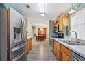 Well-lit kitchen with stainless steel appliances, white countertops, wooden cabinets, and vinyl flooring, perfect for modern cooking at 37338 Sandra Ave, Zephyrhills, FL 33542