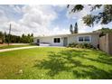 Charming single-story home featuring a well-manicured lawn, vibrant plants and a green door at 3951 72Nd N St, St Petersburg, FL 33709