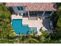 Aerial view of a backyard with a beautiful pool, patio, and screened-in porch surrounded by tropical foliage at 4612 W Lowell Ave, Tampa, FL 33629