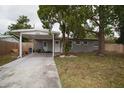 Single-story home with carport, featuring a freshly painted exterior, landscaped front yard, and mature trees at 5205 98Th N Ter, Pinellas Park, FL 33782