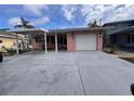 Charming pink single-story home featuring a covered carport and white garage door, complemented by tropical palm tree accents at 5445 Manatee Point Dr, New Port Richey, FL 34652