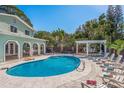 Inviting backyard pool with lounge chairs, a pergola, and lush tropical landscaping at 8240 144Th Ln, Seminole, FL 33776