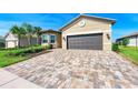 Wide brick driveway leading to a two-car garage with a well-manicured lawn at 15525 Corona Del Mar Dr, Wimauma, FL 33598