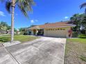 Inviting single-story home featuring a spacious driveway and lush, green lawn at 1599 Mcauliffe Ln, Palm Harbor, FL 34683