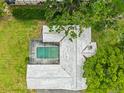 Aerial view of a house featuring a screened pool, lush green lawn, and mature trees at 1675 Robin Hood Ln, Clearwater, FL 33764