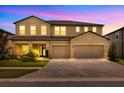 Warmly lit two-story home featuring a three-car garage and a welcoming front entrance at 17845 Cortes Creek Blvd, Spring Hill, FL 34610