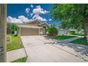 Inviting home with a large driveway, lush green lawn, and mature landscaping at 19247 Otters Wick Way, Land O Lakes, FL 34638