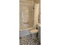 Bright bathroom featuring marble tiled walls and a bathtub with a shower and safety bars at 2468 Florentine Way # 26, Clearwater, FL 33763