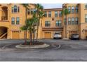 A view of the yellow condo building with garages and tropical landscaping at 2739 Via Capri # 1011, Clearwater, FL 33764