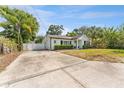 The home has a concrete driveway, manicured bushes, palm tree, and a white fence at 3125 W Fielder St, Tampa, FL 33611