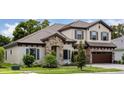 Charming two-story home with stone accents, a tile roof, a three-car garage, and manicured landscaping at 4523 Foley Grove Dr, Valrico, FL 33596
