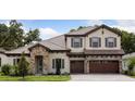 Charming two-story home with stone accents, a tile roof, a three-car garage, and manicured landscaping at 4523 Foley Grove Dr, Valrico, FL 33596