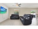Living room with tile floors, ceiling fan and leather seating with a large television at 5067 Sable Chime Dr, Wimauma, FL 33598