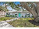 Inviting single-story home with a turquoise door, enhanced by a lush, green lawn at 526 62Nd Ne Ave, St Petersburg, FL 33702