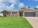 Well-maintained single-story home with a lush lawn, gray garage door, and neutral paint at 5470 Bayshore Dr, Seminole, FL 33772