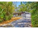 View of the home with gray and white exterior nestled among lush, mature landscaping and trees at 612 Sw Beverly Ave, Largo, FL 33770