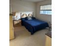 Cozy bedroom with patterned carpet, window, wooden bedside table, and blue quilt on the bed at 1200 37Th N St # 403, St Petersburg, FL 33713