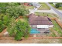 Aerial view of a fenced backyard with a screened-in pool, surrounded by lush greenery and mature trees at 12279 Elmore Dr, Spring Hill, FL 34609