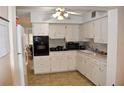 A compact kitchen featuring white cabinets, black appliances, and durable tile flooring at 2463 Brazilia Dr # 43, Clearwater, FL 33763