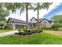 Charming one-story home featuring lush landscaping, brick-lined flowerbeds, and a two-car garage at 3716 Janus Way, Palm Harbor, FL 34685