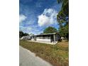 View of single story home, with lush lawn, mature trees, and a screened in porch at 6099 107Th N Ave, Pinellas Park, FL 33782