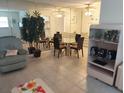A bright living room featuring tile flooring, a decorative tree, and a view into the adjacent dining area at 650 Pinellas Point S Dr # 101, St Petersburg, FL 33705