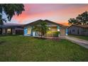 Beautiful single-story home with a manicured lawn, and an attached garage during sunset at 843 Greenfield Dr, Palm Harbor, FL 34684