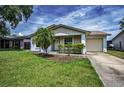 Beautiful single-story home featuring a manicured lawn, a palm tree and an attached garage at 843 Greenfield Dr, Palm Harbor, FL 34684